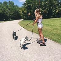 Image of Emily Boulin riding a skateboard with her dogs