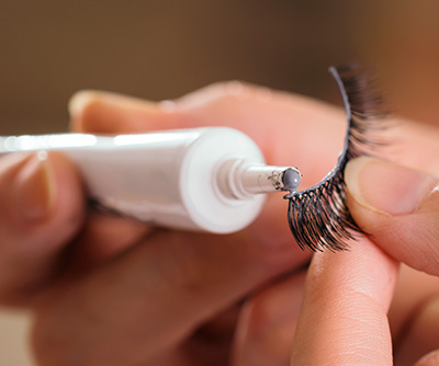 hand holding lash and applying adhesive to strip