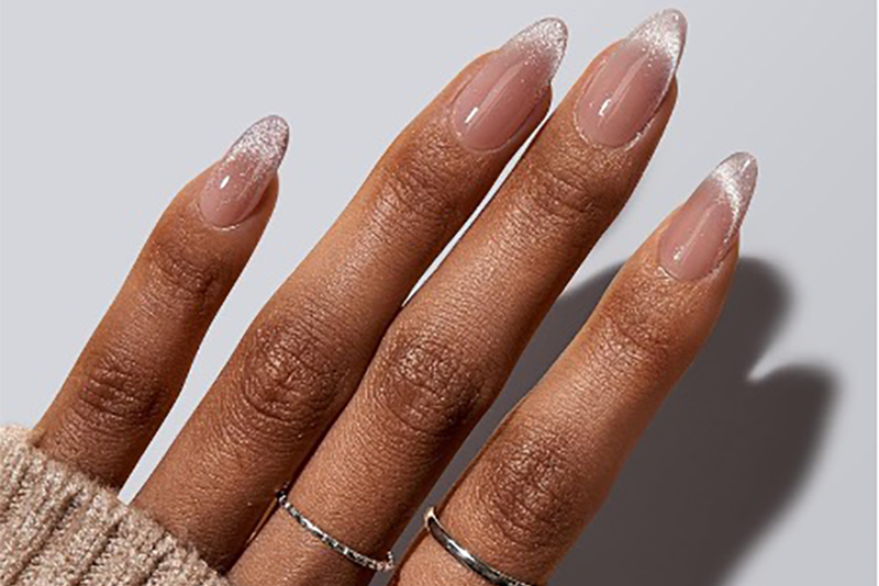 A hand with sheer, shimmering French tip cat eye nails.