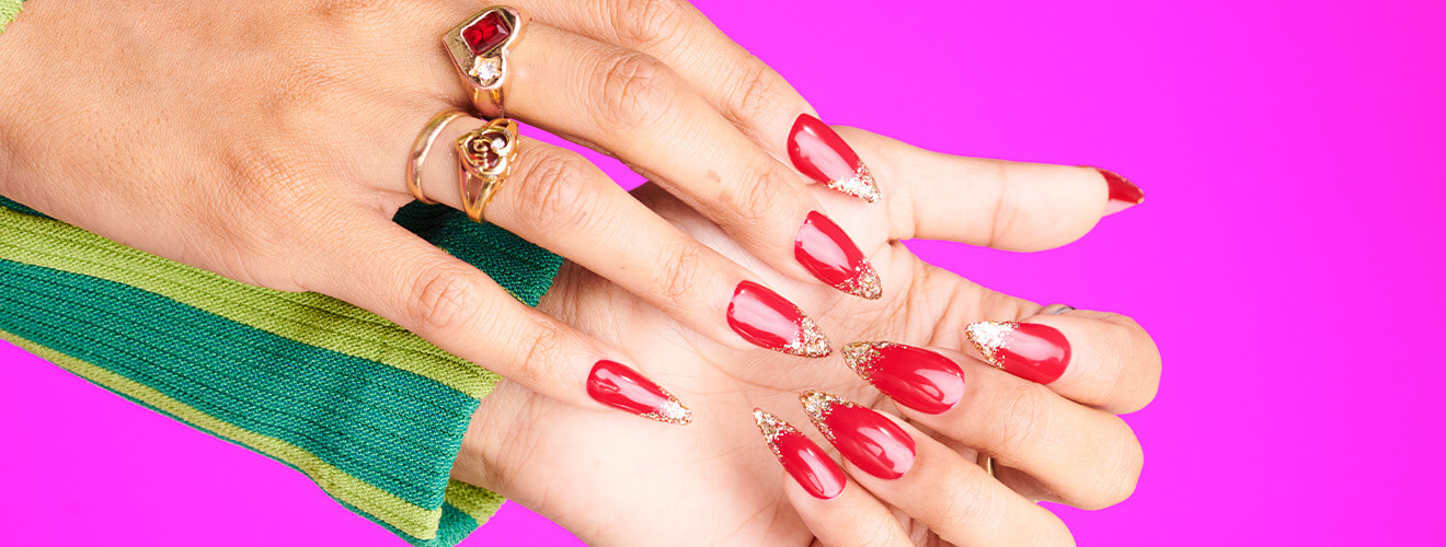 Red acrylic nails with gold dusted tips.