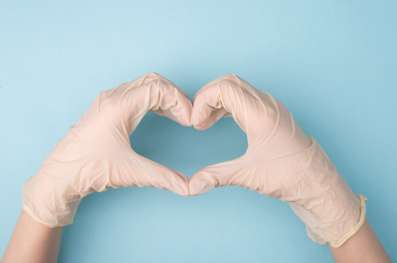 two gloved hands forming heart on blue background